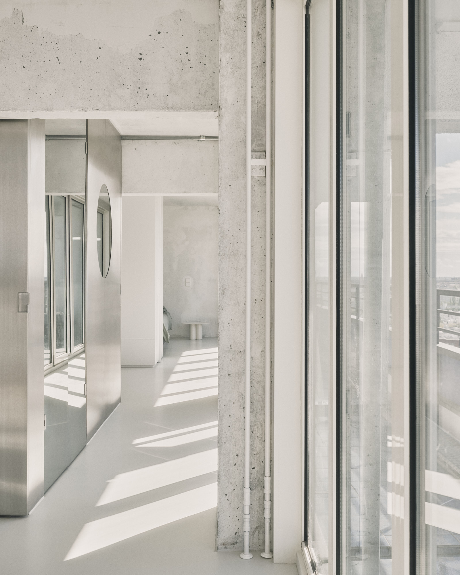L48 interior showing exposed concrete columns, mirrored panels, and floor-to-ceiling windows